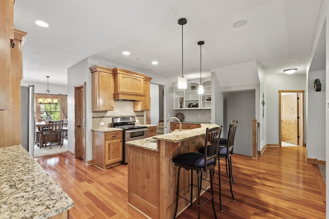 kitchen with light wood-type flooring, a sink, open shelves, stainless steel appliances, and decorative backsplash