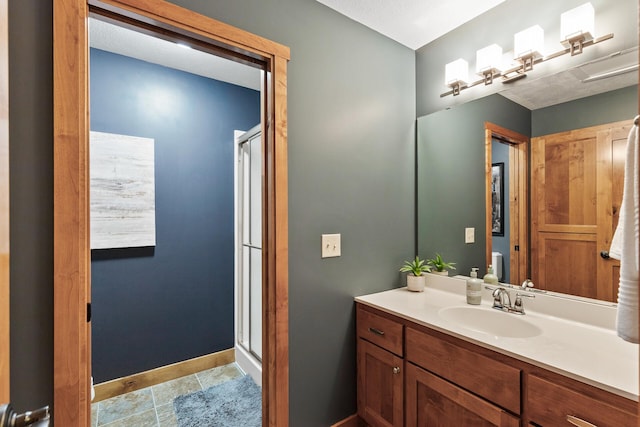 bathroom featuring vanity, baseboards, and a stall shower