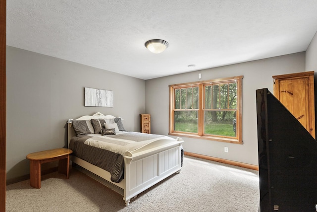 bedroom with light colored carpet, baseboards, and a textured ceiling