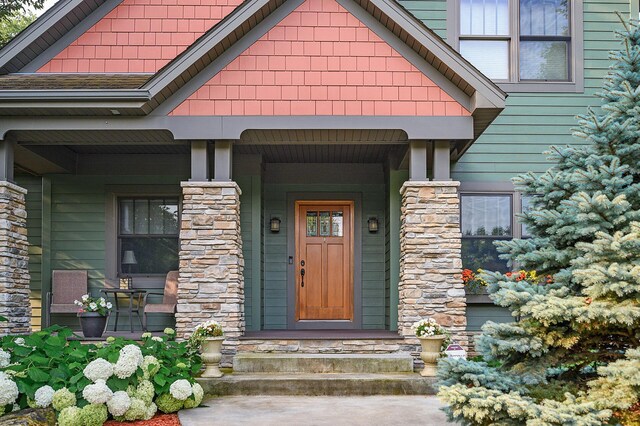 property entrance with a porch and roof with shingles