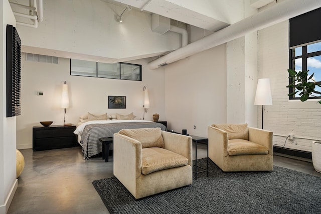 bedroom featuring a towering ceiling, rail lighting, and concrete flooring