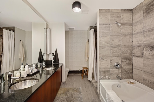 full bathroom featuring dual bowl vanity, hardwood / wood-style flooring, shower / tub combo with curtain, and toilet