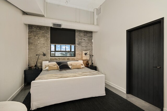 bedroom featuring brick wall and concrete floors