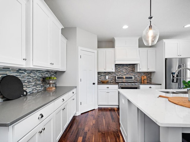 kitchen featuring white cabinets, hanging light fixtures, custom range hood, and appliances with stainless steel finishes