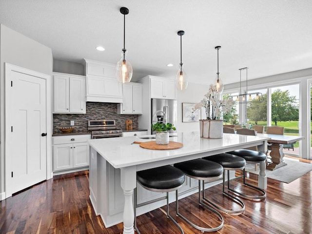 kitchen with appliances with stainless steel finishes, backsplash, white cabinetry, and a large island with sink