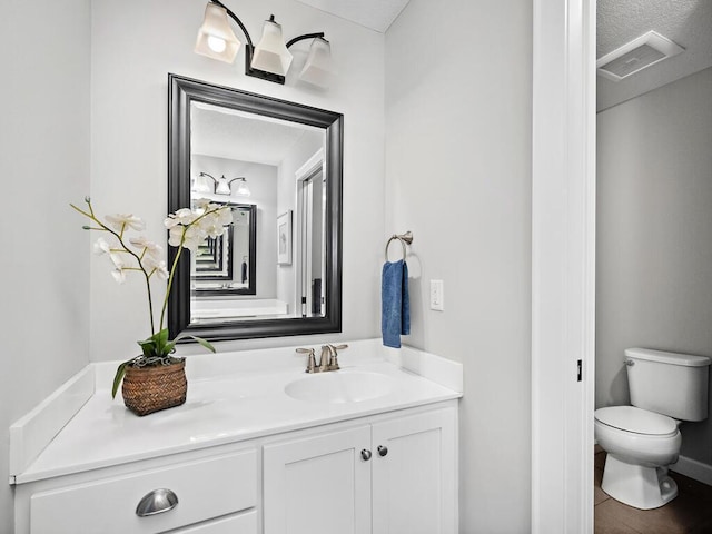 bathroom with vanity, toilet, and a textured ceiling