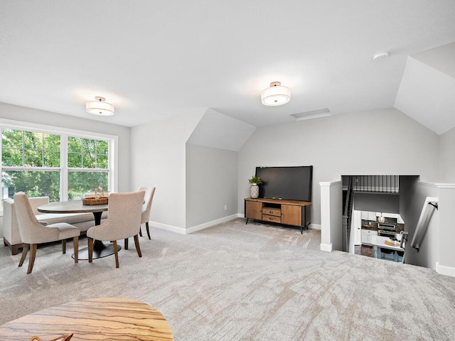 carpeted dining space with lofted ceiling