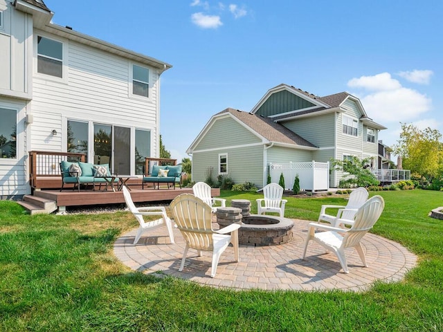 back of house with a wooden deck, a patio area, a yard, and an outdoor living space with a fire pit