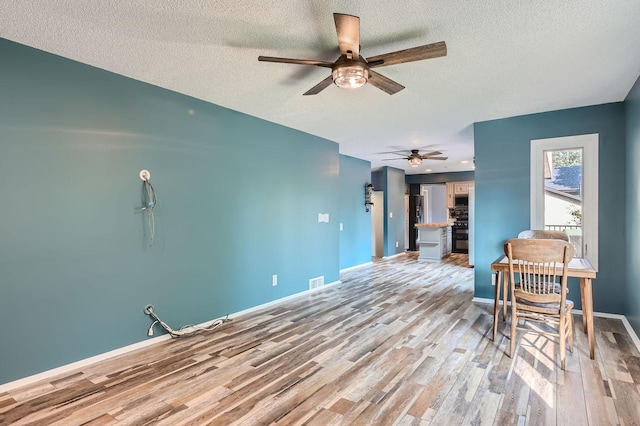 unfurnished room featuring a textured ceiling, light hardwood / wood-style floors, and ceiling fan