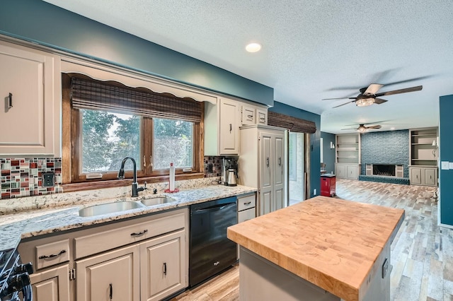 kitchen with ceiling fan, sink, a brick fireplace, light hardwood / wood-style flooring, and black appliances