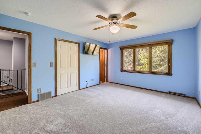 unfurnished bedroom with a textured ceiling, carpet, and ceiling fan