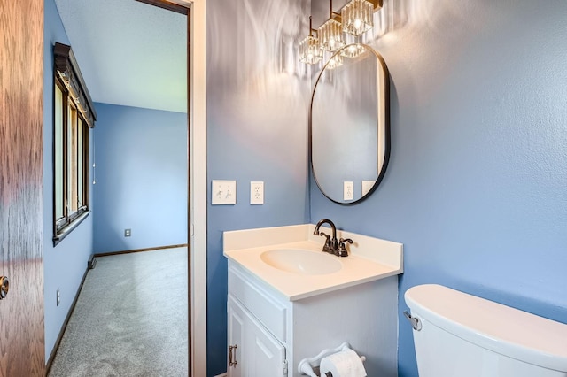 bathroom featuring a notable chandelier, vanity, and toilet