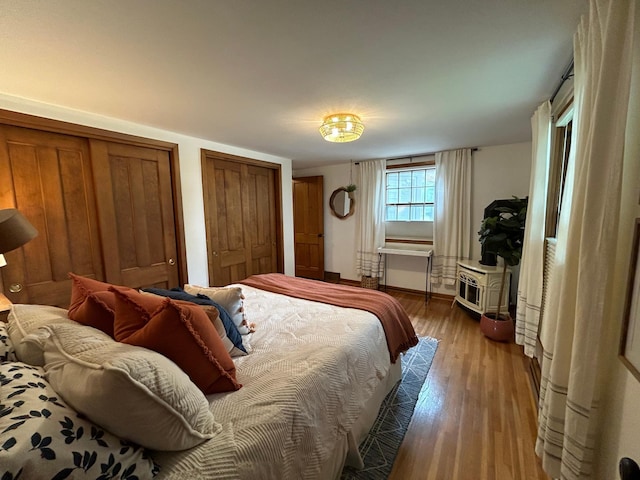 bedroom featuring light wood-type flooring and multiple closets