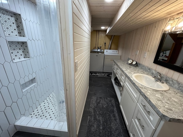 bathroom with vanity, independent washer and dryer, walk in shower, and wooden walls