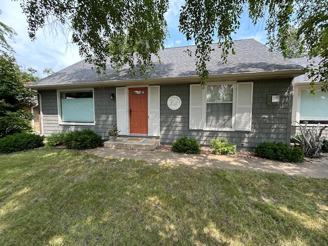 ranch-style home with a shingled roof and a front lawn