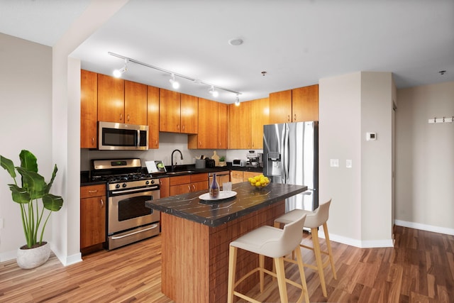 kitchen featuring sink, a center island, light hardwood / wood-style flooring, a kitchen breakfast bar, and stainless steel appliances