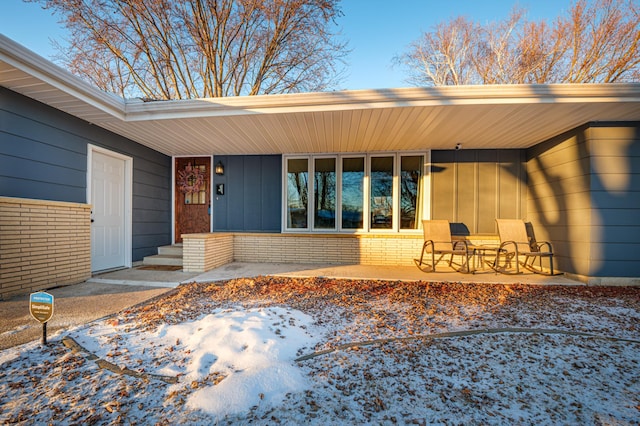 snow covered property entrance with a porch