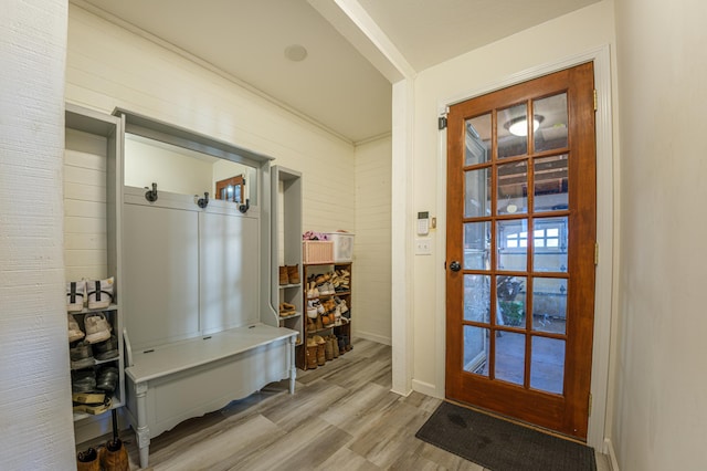 mudroom with wood walls, light wood-type flooring, and ornamental molding