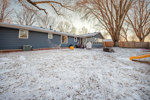 snow covered house with a sunroom and central AC unit