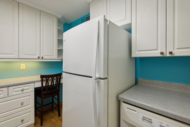 kitchen featuring white appliances, light hardwood / wood-style flooring, white cabinetry, and built in desk