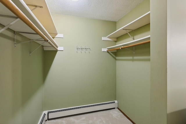 walk in closet with light colored carpet and a baseboard heating unit