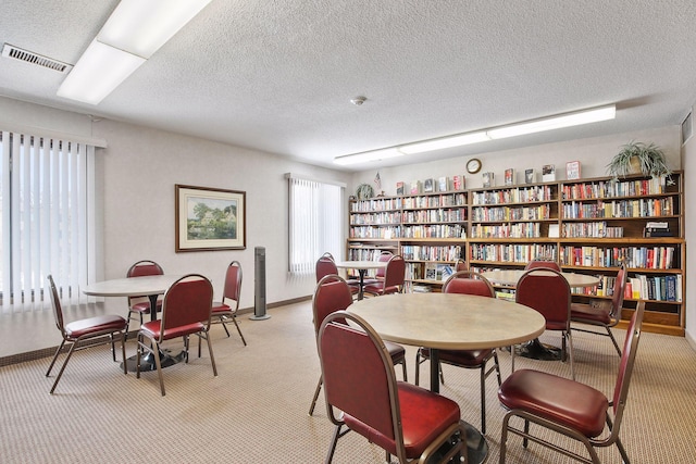 dining room featuring light carpet and a textured ceiling