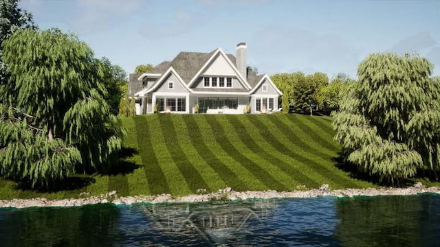 rear view of house featuring a lawn, a chimney, and a water view