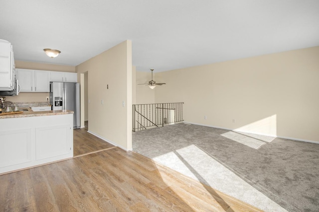 kitchen featuring ceiling fan, light carpet, stainless steel fridge, and white cabinetry