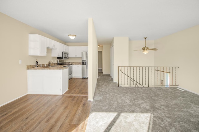 interior space with light wood-type flooring, white cabinetry, stainless steel appliances, kitchen peninsula, and ceiling fan