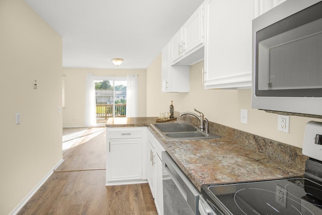 kitchen featuring appliances with stainless steel finishes, kitchen peninsula, sink, white cabinetry, and light wood-type flooring