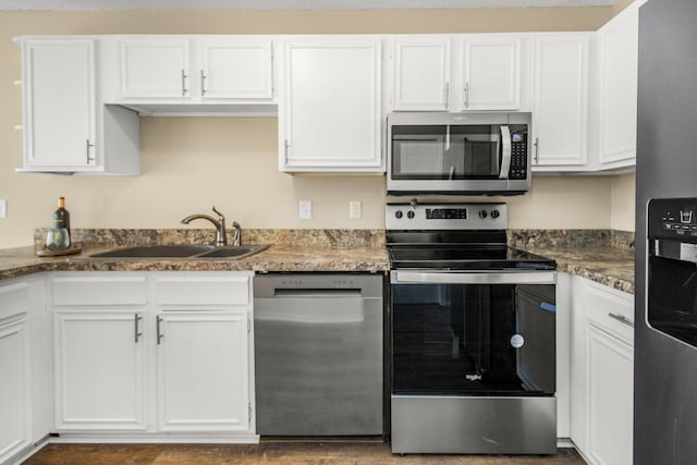 kitchen with white cabinets, dark stone countertops, stainless steel appliances, and sink