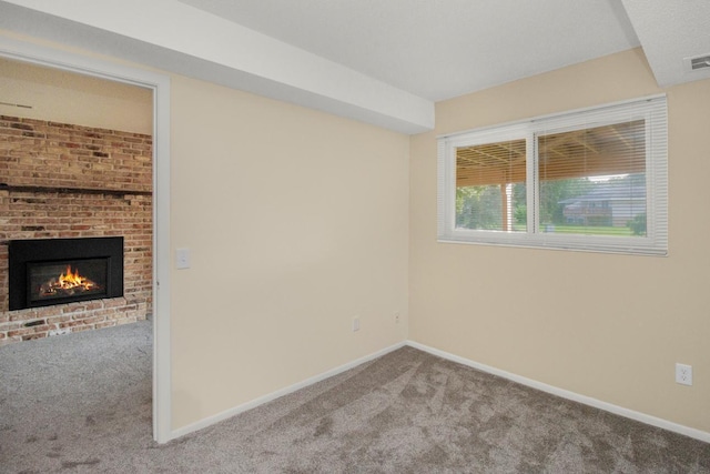 spare room featuring light colored carpet and a brick fireplace