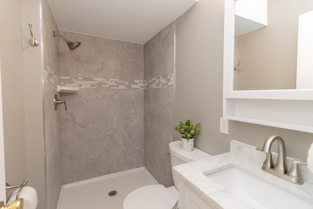 bathroom with tiled shower, vanity, and toilet