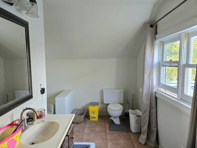 bathroom with toilet, vanity, and vaulted ceiling