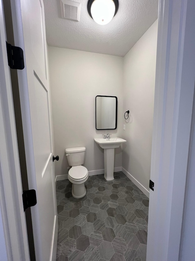 bathroom featuring toilet, sink, and a textured ceiling