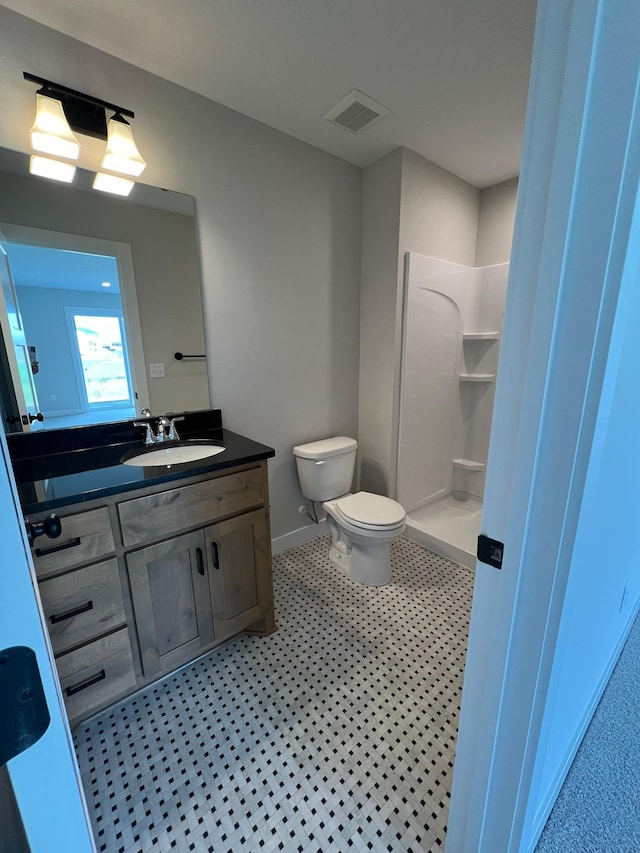 bathroom featuring a shower, vanity, and toilet