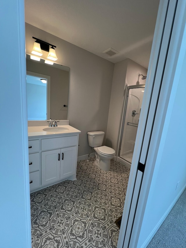 bathroom with vanity, tile patterned floors, a shower with door, and toilet