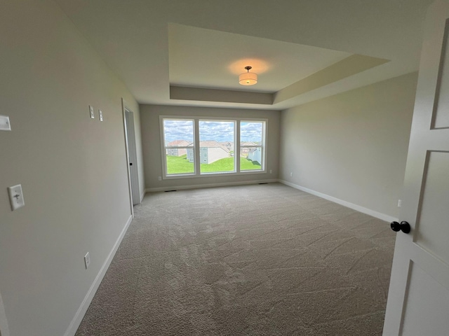 carpeted spare room featuring a tray ceiling