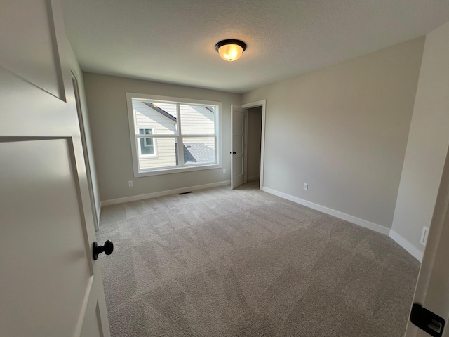 carpeted empty room with a textured ceiling