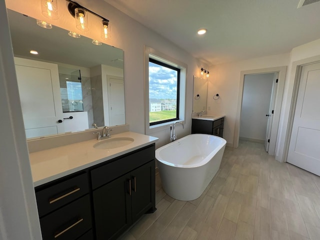 bathroom featuring wood finished floors, vanity, a walk in shower, and a freestanding bath