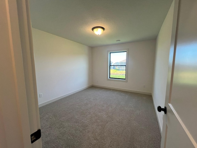 carpeted empty room with a textured ceiling and baseboards