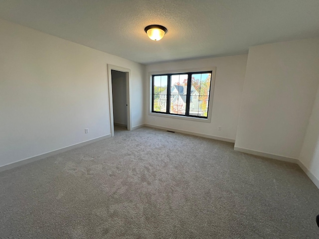 unfurnished room featuring visible vents, baseboards, a textured ceiling, and light colored carpet