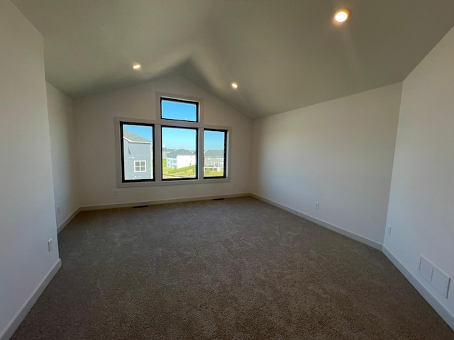 unfurnished room with vaulted ceiling and dark carpet