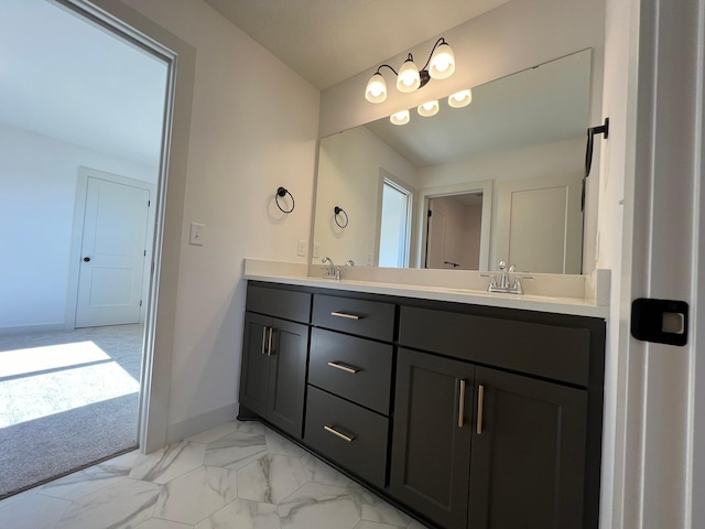 bathroom featuring double vanity, marble finish floor, baseboards, and a sink
