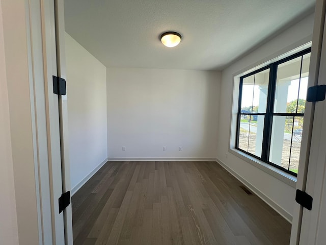 unfurnished room with a textured ceiling and dark wood-type flooring