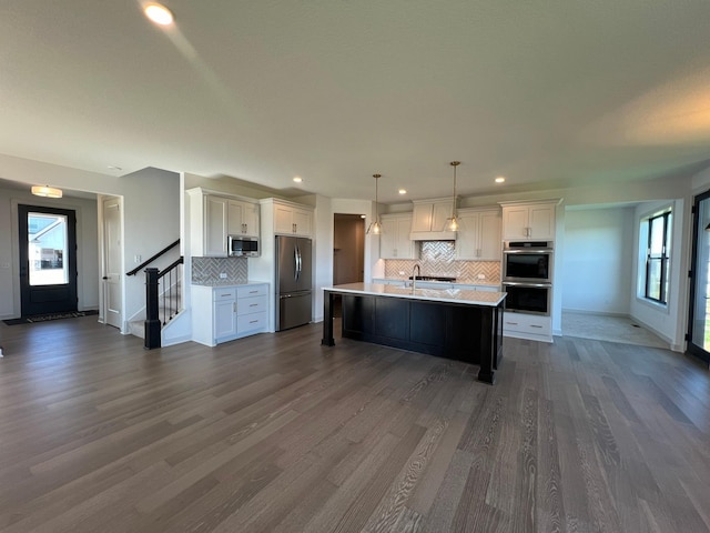 kitchen with pendant lighting, white cabinetry, dark hardwood / wood-style flooring, a kitchen island with sink, and stainless steel appliances