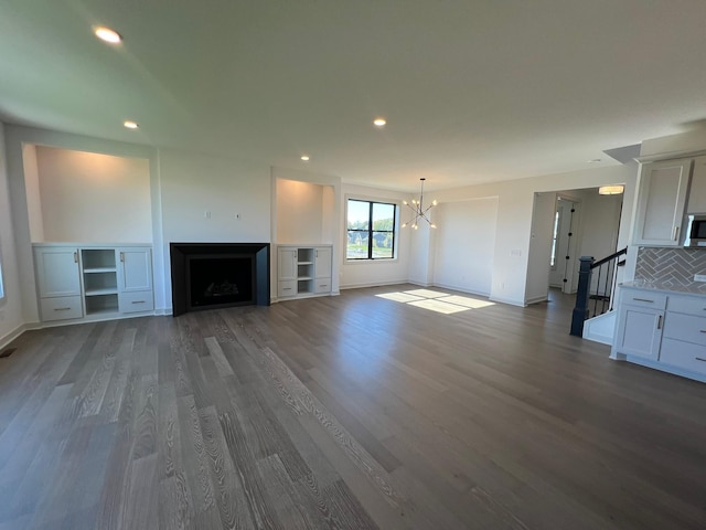 unfurnished living room with baseboards, recessed lighting, a notable chandelier, wood finished floors, and a fireplace