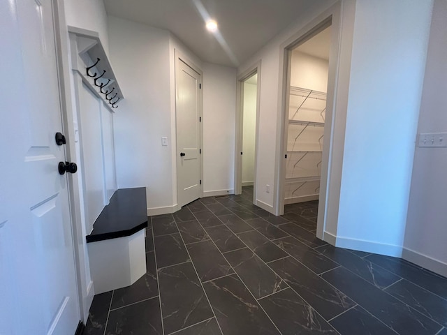 corridor with marble finish floor and baseboards