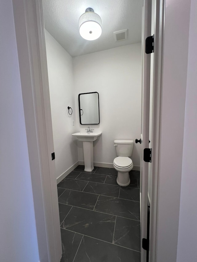 bathroom featuring a textured ceiling and toilet