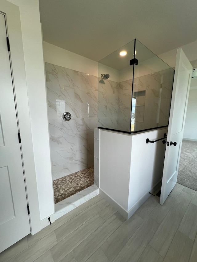 bathroom with wood finish floors, a marble finish shower, and recessed lighting